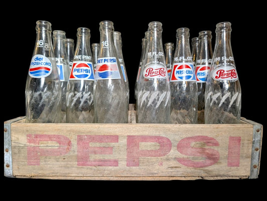 Vintage Pepsi bottles in a wooden pepsi crate from the 50s with clear labels.